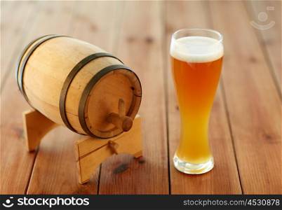 brewery, drinks and alcohol concept - close up of draft lager beer in glass and wooden barrel on table