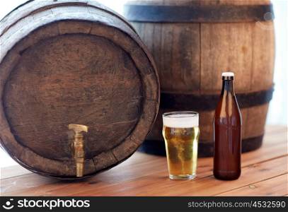 brewery, drinks and alcohol concept - close up of old beer barrel, glass and bottle on wooden table