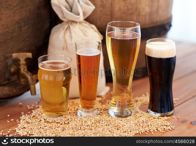 brewery, drinks and alcohol concept - close up of old beer barrel, glasses and bag with malt on wooden table