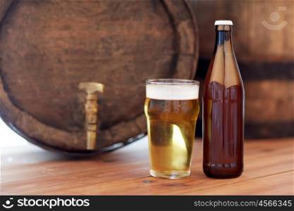 brewery, drinks and alcohol concept - close up of old beer barrel, glass and bottle on wooden table