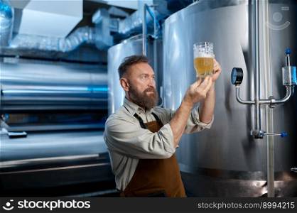 Brewery worker looking at freshly made beer in glass mug. Brewing factory technological process concept. Brewery worker looking at freshly made beer in glass mug