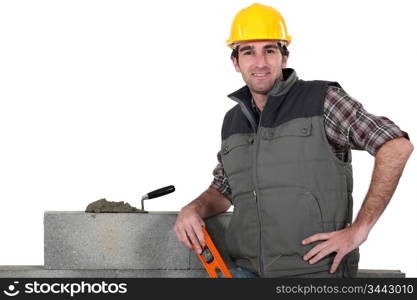 bricklayer posing near wall with arm akimbo