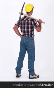 bricklayer seen from behind with pickaxe over his shoulder