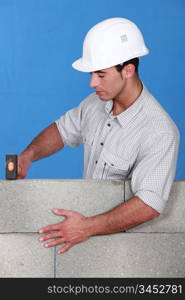 Bricklayer tapping down a block wall