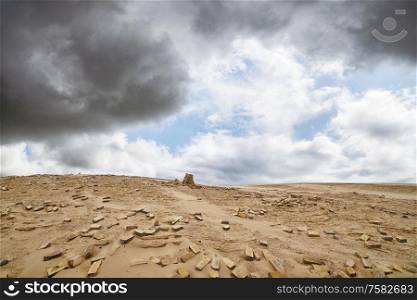 Bricks in a dry desert in cloudy weather with a stack of stones