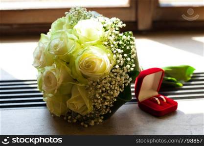 bridal bouquet and a box with the rings on the window
