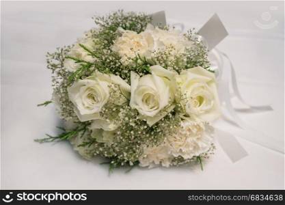 Bridal bouquet of white rose on white fabric background
