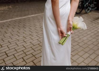 Bridal bouquet. Wedding. The slim woman in a white dress holds a beautiful bouquet of white flowers outdoors.. Bridal bouquet. Wedding. The slim woman in a white dress holds a beautiful bouquet of white flowers outdoors