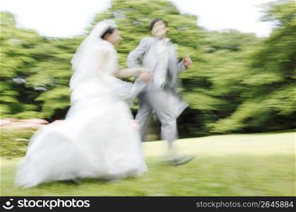 Bridal couple running in garden