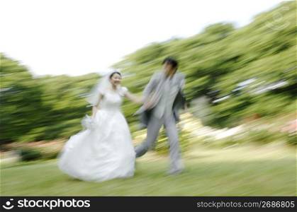 Bridal couple running in garden