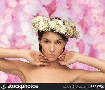 bridal, spring and beauty concept - young woman wearing wreath of flowers on floral background