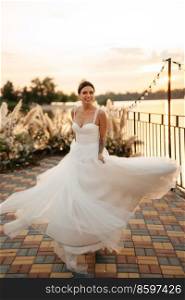 bride against the background of a yellow sunset on a pier near the river
