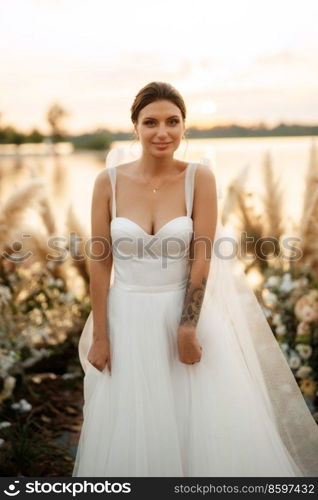 bride against the background of a yellow sunset on a pier near the river