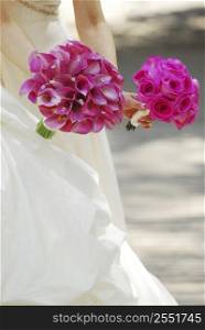 Bride and bridesmaid holding bouquets of pink flowers