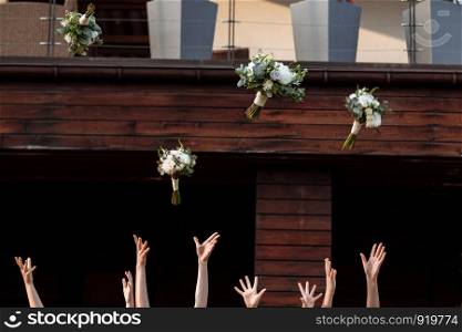 bride and bridesmaids throwing bouquets up, sunny wedding reception. joyful moment. bride with girls having fun in wedding morning