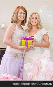 Bride and Friend standing Together holding gift at Bridal Shower
