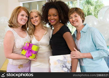 Bride and Friends standing Together holding gifts at Bridal Shower