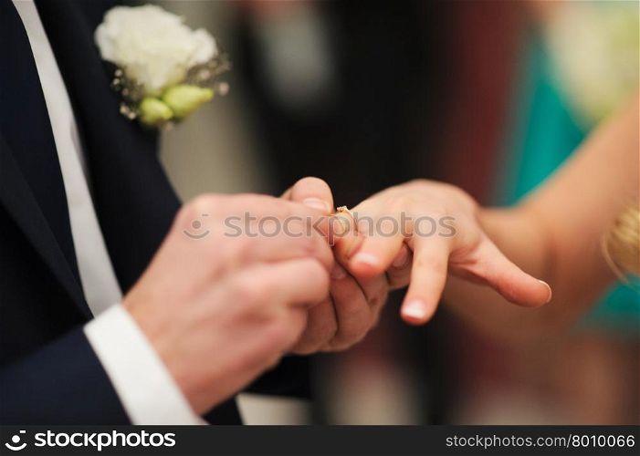 bride and groom are changing rings on wedding