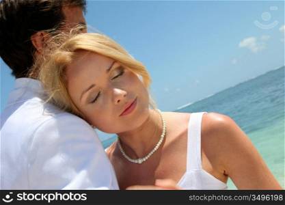 Bride and groom embracing by the sea