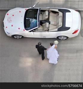 bride and groom going to white car