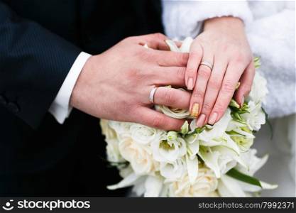 Bride and groom holding hands outdoors. Beautiful wedding rings.
