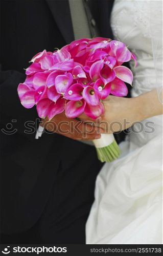 Bride and groom holding hands with wedding bouquet.