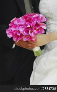 Bride and groom holding hands with wedding bouquet.