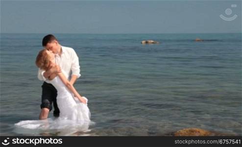 bride and groom kissing in the water at the beach
