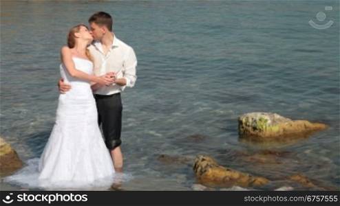 bride and groom kissing in the water at the beach