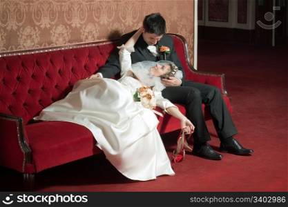 Bride and groom looking at each other on a sofa