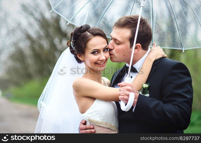 bride and groom on a rainy wedding day walking under an umbrella