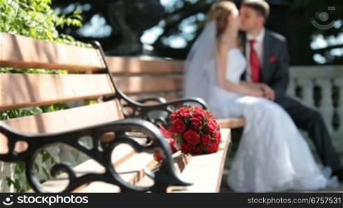bride and groom sit on a bench in the park