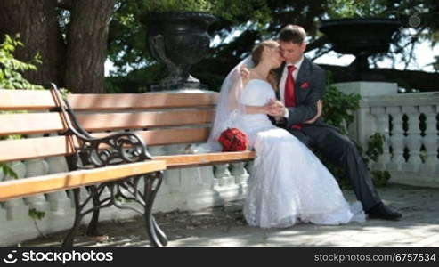 bride and groom sit on a bench in the park