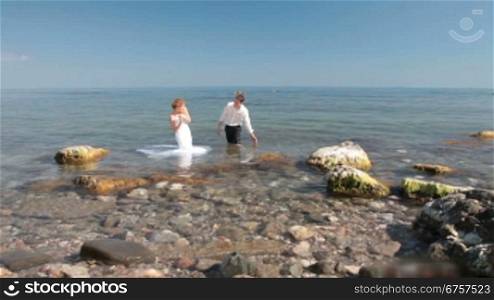 bride and groom splashes in the water at the sea