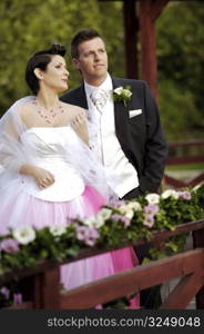 Bride and groom standing side by side outdoors, smiling, portrait