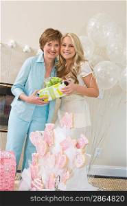 Bride and her Friend standing Together holding gift at Bridal Shower