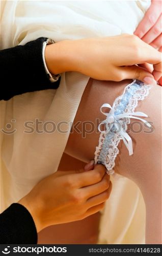 Bride at the clothes shop for wedding dresses; she is choosing a dress and wears a garter
