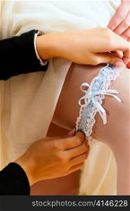 Bride at the clothes shop for wedding dresses; she is choosing a dress and wears a garter