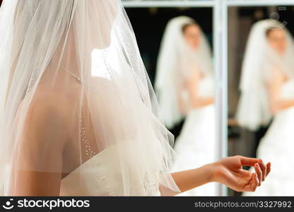 Bride at the clothes shop for wedding dresses; she is choosing a dress