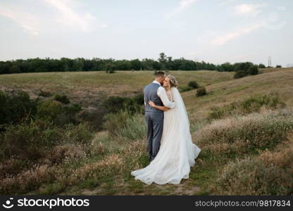 bride blonde girl and groom in a field at sunset light