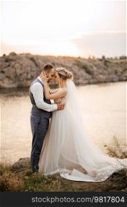 bride blonde girl and groom near the river at sunset light