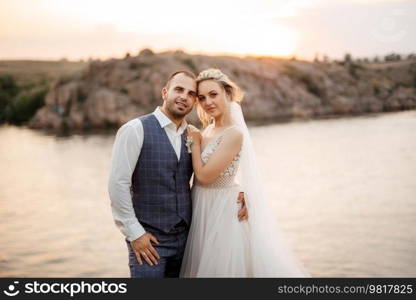 bride blonde girl and groom near the river at sunset light