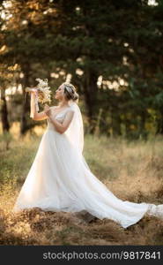 bride blonde girl with a bouquet in the forest in the sunset light