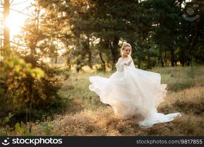 bride blonde girl with a bouquet in the forest in the sunset light