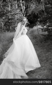 bride blonde girl with a bouquet in the forest in the sunset light