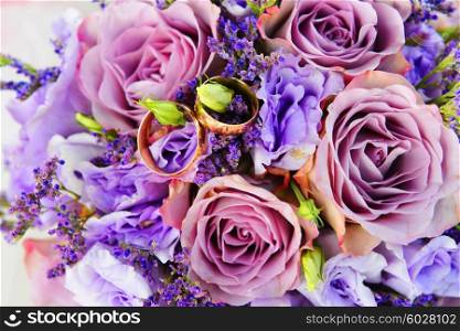 bride bouquet of purple flowers with wedding gold rings
