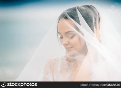 bride close-up under a veil against a background of blue sky and black sea