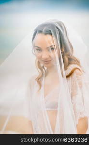 bride close-up under a veil against a background of blue sky and black sea