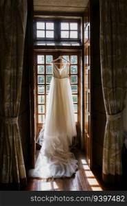 Bride dress pending on a window before the wedding. KEILA & RUB?