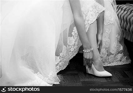 Bride dresses shoes before the wedding ceremony. Black and white photography